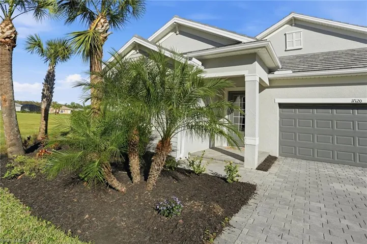 View of front of home with stucco siding, decorative driveway, and a porch