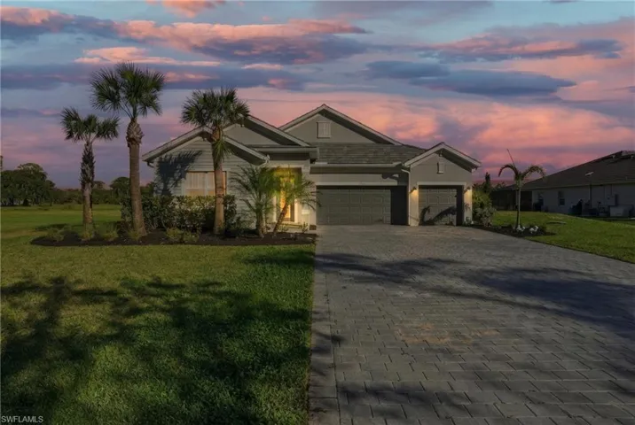 View of front of house featuring an attached garage, decorative driveway, a front lawn, and stucco siding