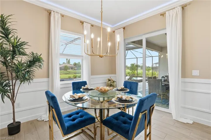 Dining space featuring a wainscoted wall, a decorative wall, plenty of natural light, crown molding, and a chandelier