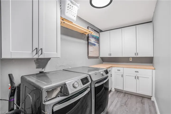 Laundry area with light wood-style flooring, cabinet space, and separate washer and dryer