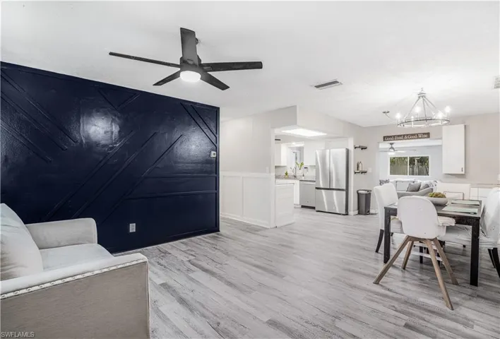 Living room featuring ceiling fan with notable chandelier, visible vents, and light wood-style flooring