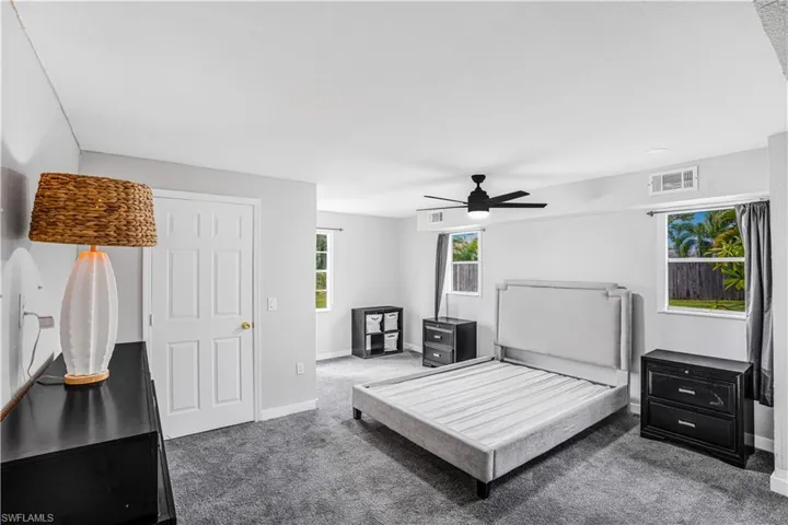 Carpeted bedroom with baseboards, ceiling fan, and visible vents