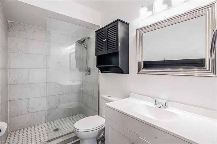 Bathroom featuring a tile shower, toilet, and vanity