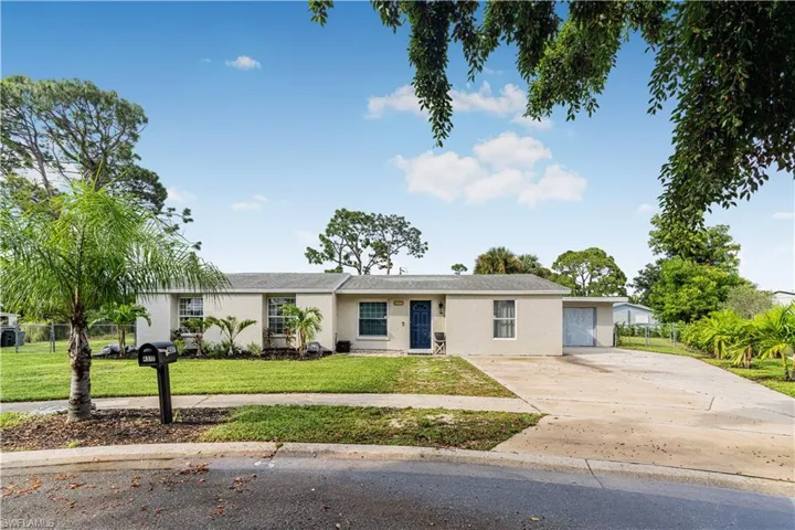 Ranch-style home with concrete driveway, stucco siding, fence, and a front lawn