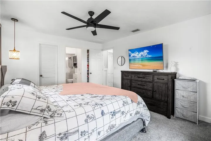 Bedroom with ensuite bath, a ceiling fan, visible vents, and carpet
