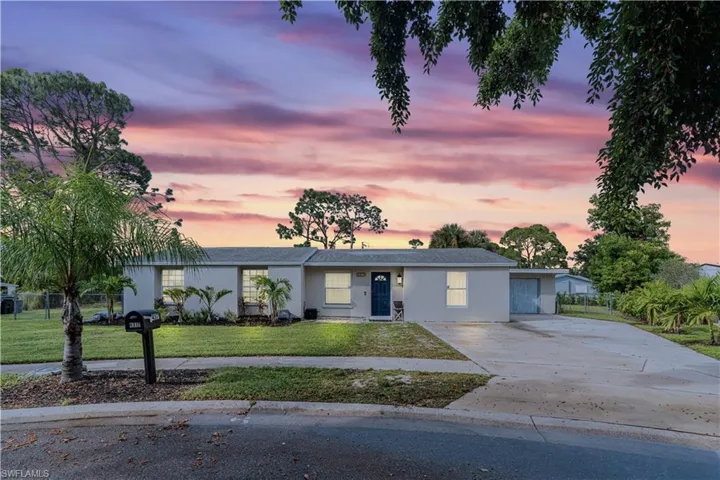 Ranch-style house with a lawn, driveway, stucco siding, and fence
