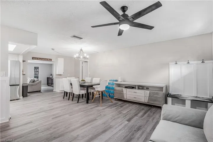 Dining space featuring visible vents, a textured ceiling, wood finished floors, and ceiling fan with notable chandelier