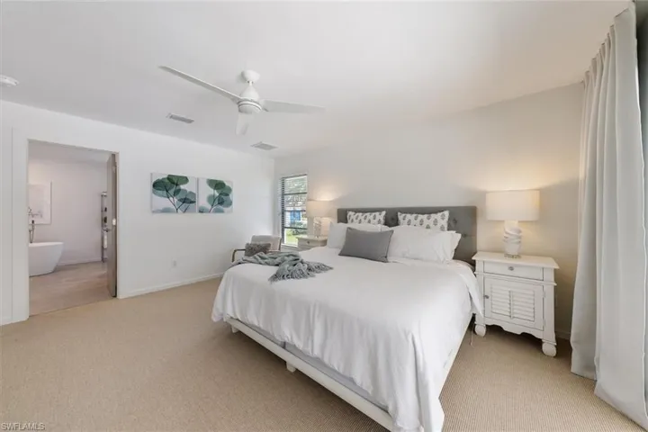 Carpeted bedroom with ensuite bath and ceiling fan