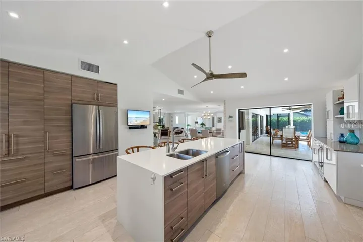 Kitchen with sink, an island with sink, lofted ceiling, light hardwood / wood-style flooring, and appliances with stainless steel finishes