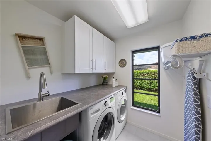 Laundry room with cabinets, independent washer and dryer, light tile patterned flooring, and sink