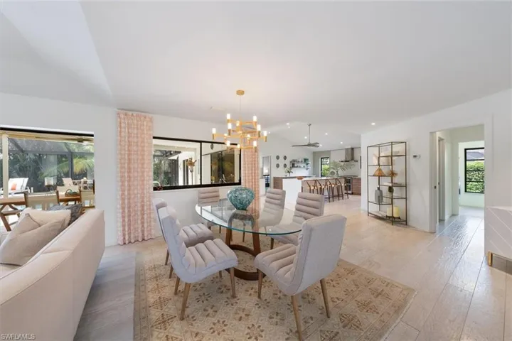 Dining space with ceiling fan with notable chandelier, light hardwood / wood-style floors, and plenty of natural light