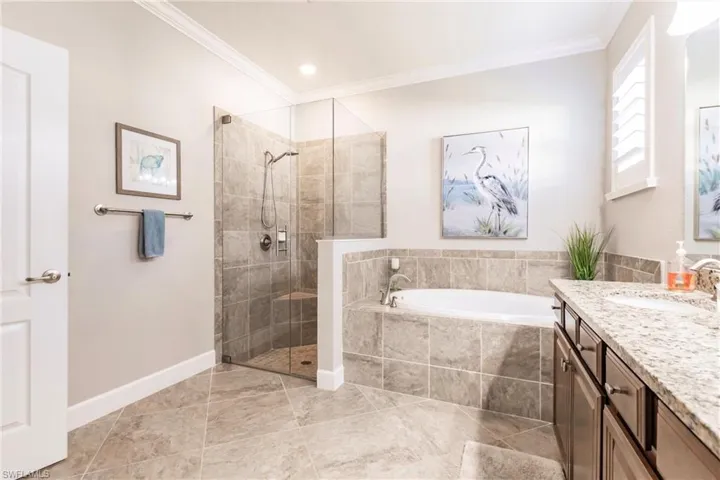 Bathroom featuring ornamental molding, vanity, and plus walk in shower