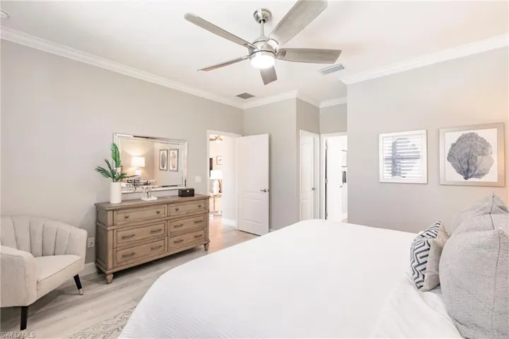 Bedroom with ceiling fan, ornamental molding, and light hardwood / wood-style flooring