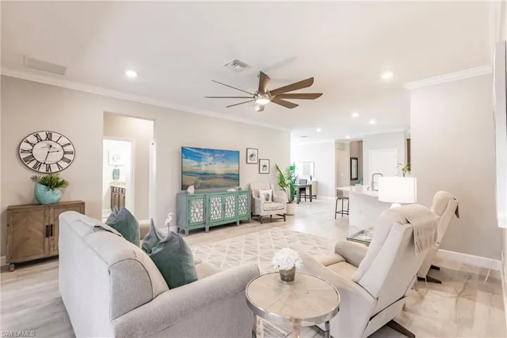 Living room with sink, ornamental molding, light hardwood / wood-style floors, and ceiling fan