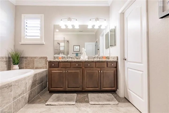 Bathroom featuring crown molding, tile patterned floors, vanity, and shower with separate bathtub