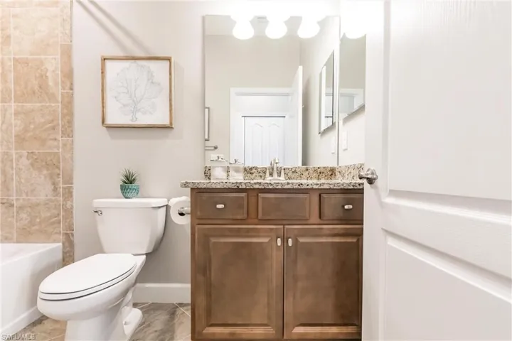Full bathroom with tiled shower / bath combo, vanity, and toilet