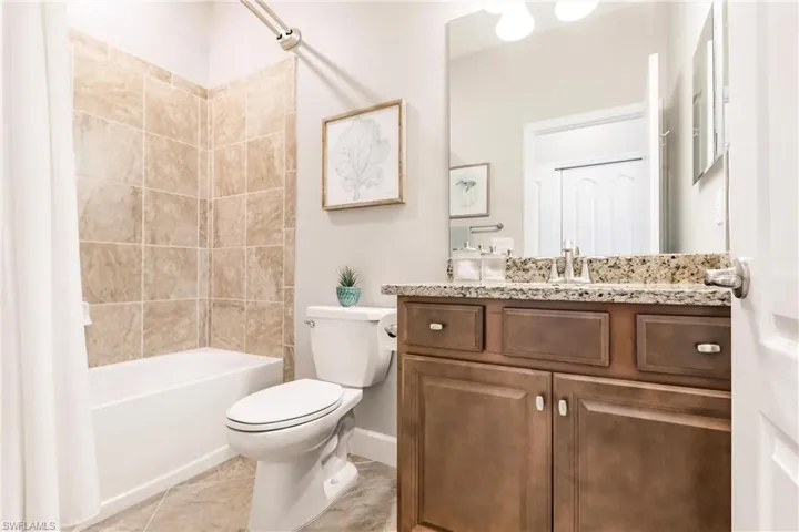 Full bathroom with vanity, tile patterned floors, shower / bath combination with curtain, and toilet