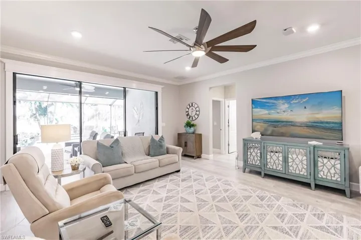 Living room with crown molding, wood-type flooring, and ceiling fan