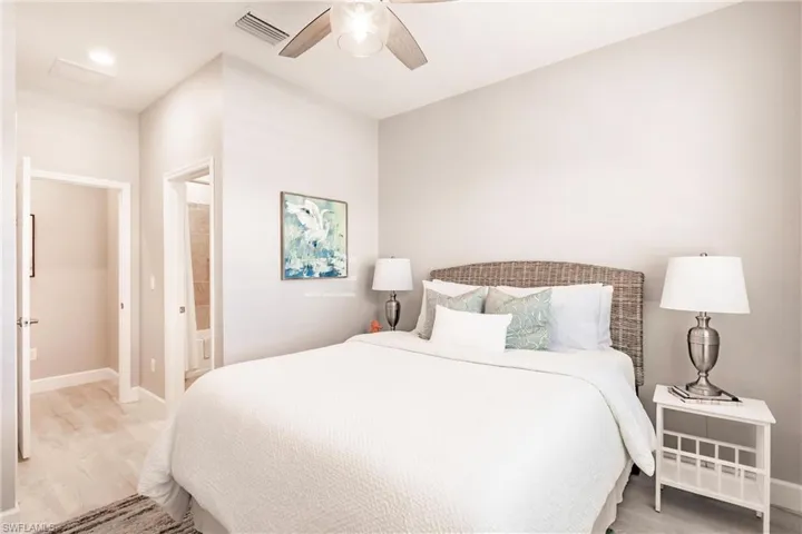Bedroom with hardwood / wood-style floors, ceiling fan, and ensuite bath
