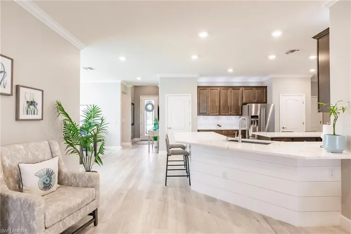 Kitchen featuring a breakfast bar, sink, high end refrigerator, light hardwood / wood-style flooring, and backsplash
