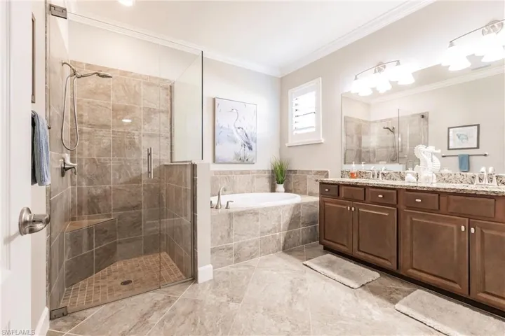 Bathroom featuring crown molding, vanity, and plus walk in shower