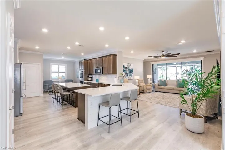 Kitchen featuring dark brown cabinetry, crown molding, appliances with stainless steel finishes, and a kitchen bar