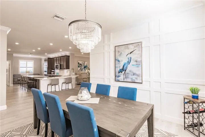 Dining area with a notable chandelier, sink, ornamental molding, and light hardwood / wood-style floors