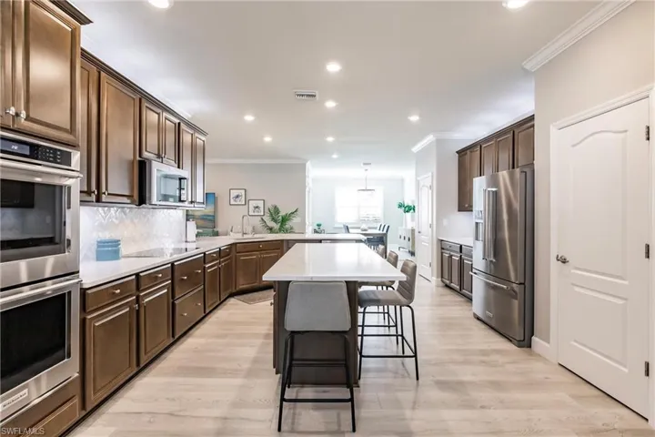 Kitchen featuring appliances with stainless steel finishes, tasteful backsplash, sink, hanging light fixtures, and crown molding