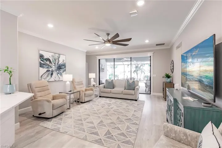 Living room featuring ceiling fan, ornamental molding, and light wood-type flooring