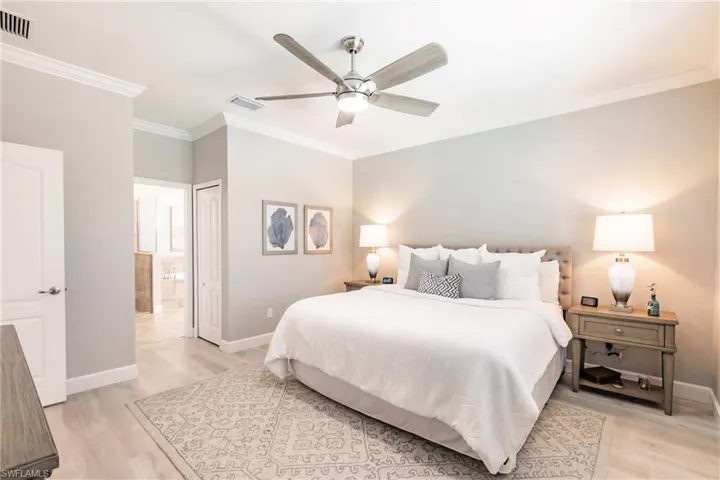 Bedroom with crown molding, ensuite bath, light hardwood / wood-style floors, and ceiling fan
