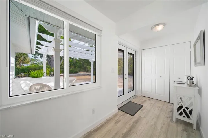 Interior space featuring light-toned wood-finish flooring, dual bi-fold panel closets, flush-mount ceiling lighting, and a large window with a stone-finish sill