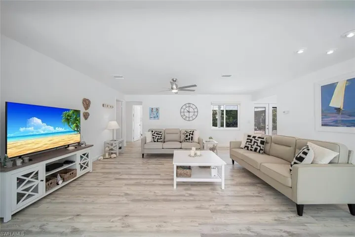 Open floor plan interior featuring wood-finish flooring, recessed lighting, and a brushed-metal ceiling fan