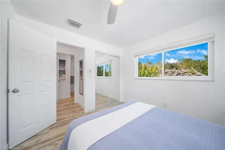Wood-finish flooring, sliding mirror-paneled closet doors, horizontal sliding windows, and a ceiling-mounted fan