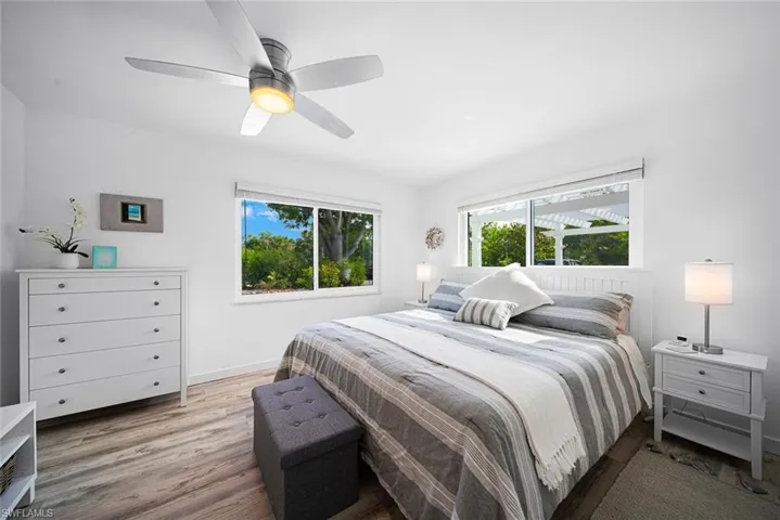 Wood-finish flooring, dual windows with exterior pergola visibility, and a contemporary ceiling fan with integrated lighting