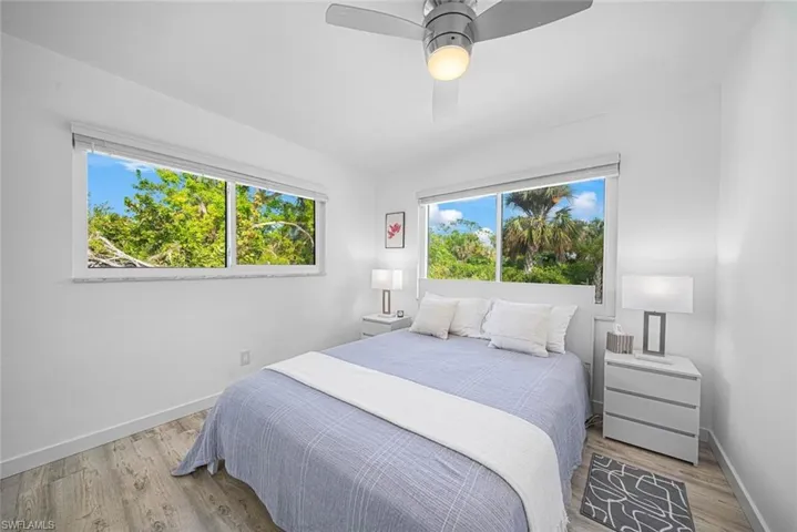 Wood-finish flooring, dual windows with exterior greenery, and a ceiling-mounted light fixture with fan
