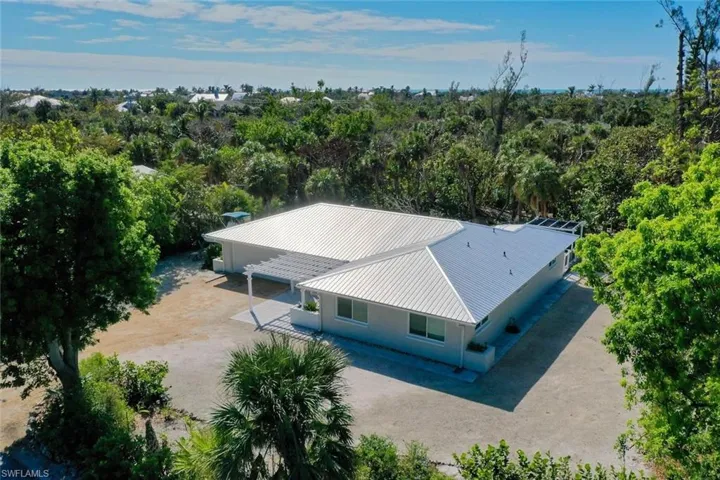 Single-story residence featuring a metal roof, pergola-covered patio, and extensive native landscaping