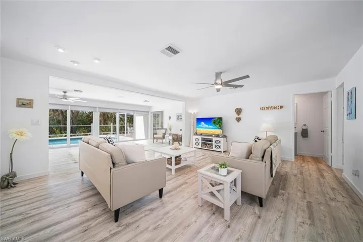 Open-concept living area featuring wood-finish flooring, recessed lighting, a ceiling fan, and sliding glass doors with exterior pool access