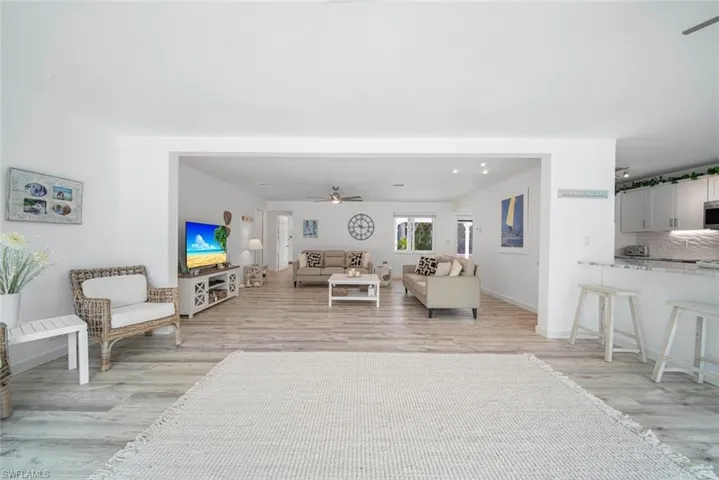Open-concept interior featuring wood-finish flooring, a kitchen breakfast bar with stone-surface countertop, and recessed lighting