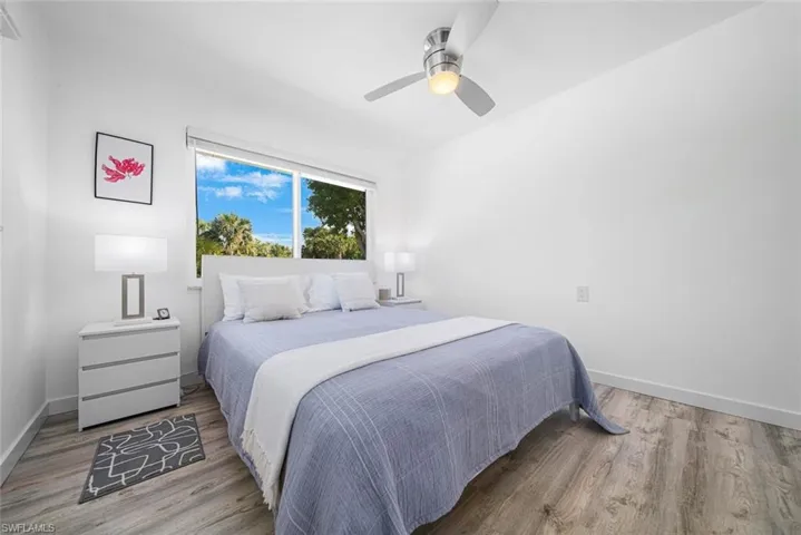 Room featuring wood-finish flooring, a neutral color palette, a large horizontal window, and a brushed nickel ceiling fan