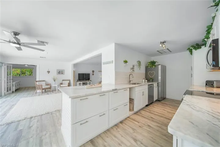 Kitchen featuring white cabinetry, stone-finish countertops, subway tile backsplash, and wood-finish flooring