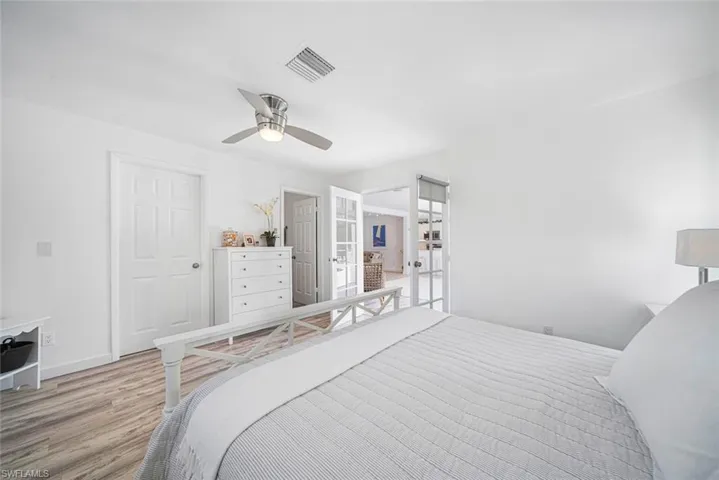 Interior room featuring wood-finish flooring, a multi-blade ceiling fan with integrated lighting, and white six-panel doors