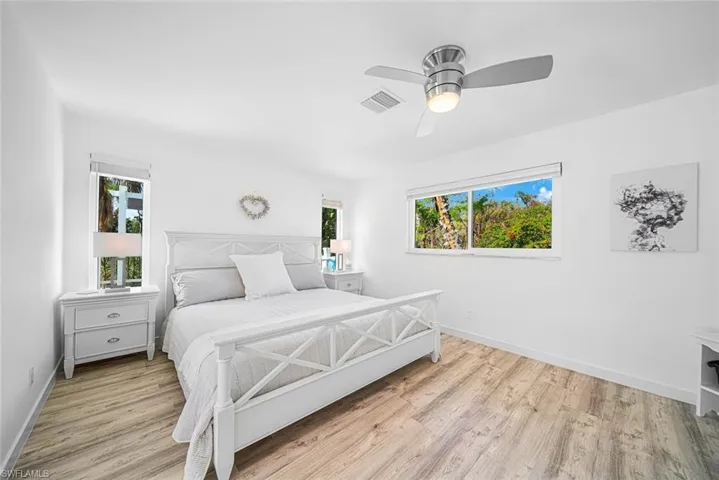 Wood-finish flooring, ceiling fan with integrated light, horizontal sliding windows, and neutral interior wall finish