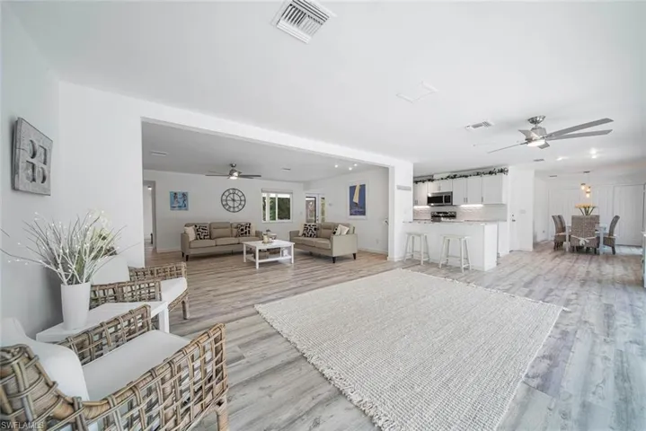 Open-concept interior featuring wood-finish flooring, white cabinetry, integrated recessed lighting, and ceiling fans