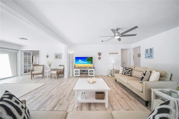 Living area featuring wood-finish flooring, a contemporary ceiling fan, recessed lighting, and white-trimmed glass French doors