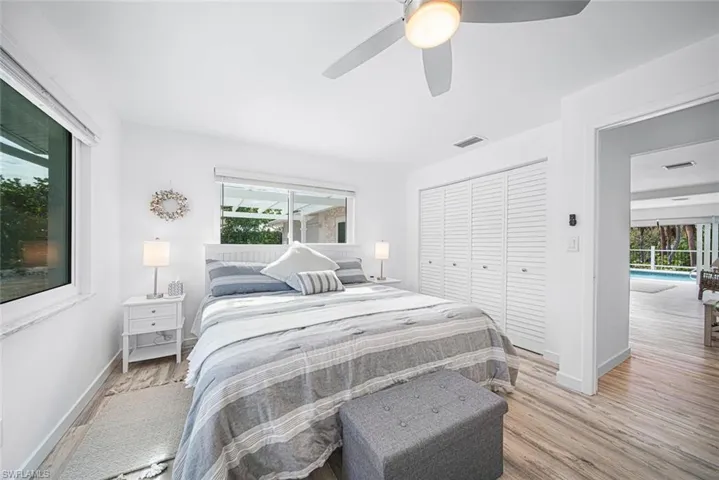 Wood-finish flooring, white louvered-door closet, ceiling fan with integrated lighting, and horizontal sliding windows