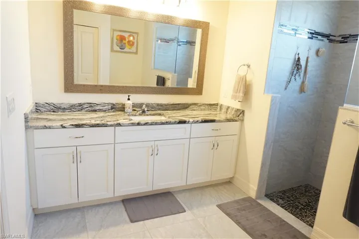 Primary Bathroom with vanity, a walk in shower, and light tile patterned flooring