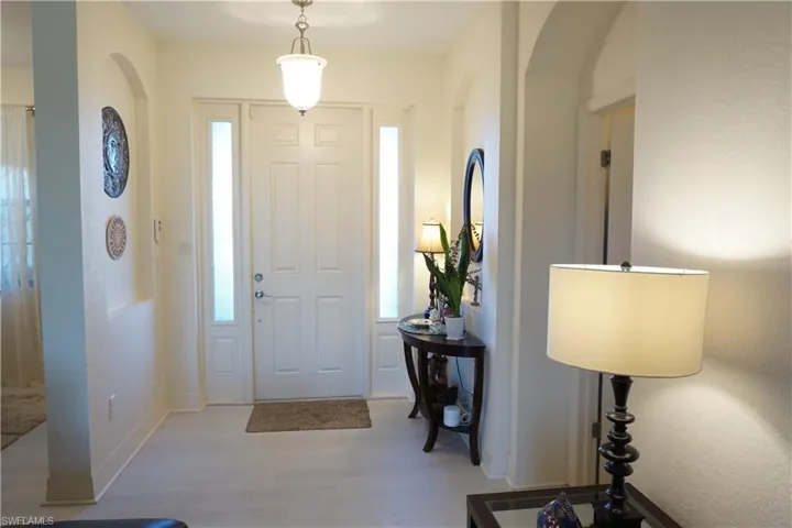 Foyer featuring light wood plank LVP floors, plenty of natural light, and arched walkways