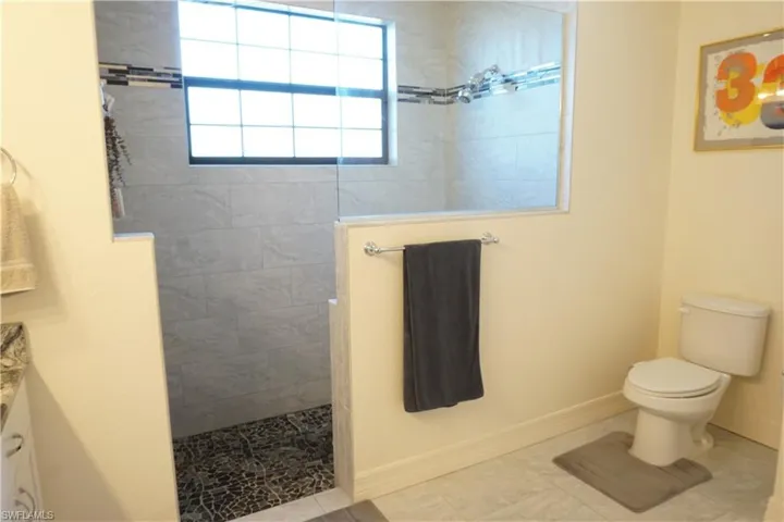 Full bath featuring vanity, walk in shower, and tile patterned flooring
