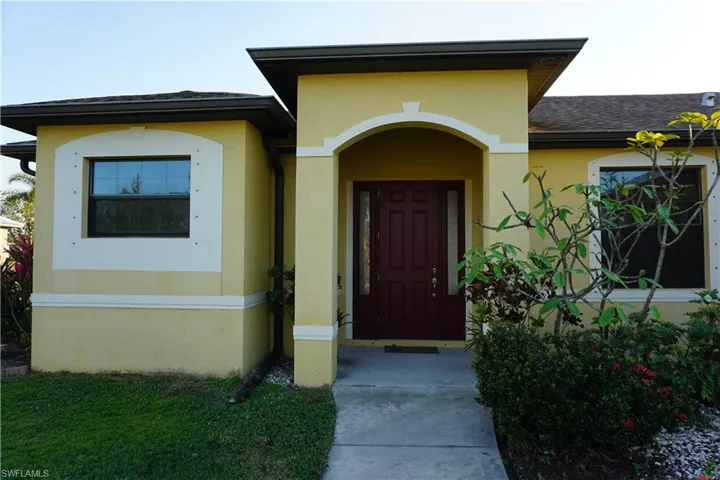 View of exterior entry featuring a shingled roof and stucco siding