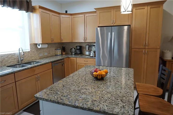 Kitchen featuring stainless steel appliances, light stone countertops, tasteful backsplash, a kitchen island and breakfast bar